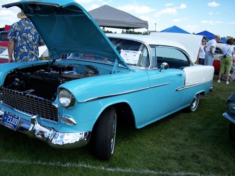1972 Ford Ranchero - A classic blue and white 1955 Chevrolet Bel Air is displayed with its hood open at an outdoor car show.