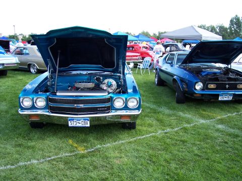 1972 Ford Ranchero - Teal 1971 Chevelle and blue 1971 Ford Mustang at a car show, both with hoods up.