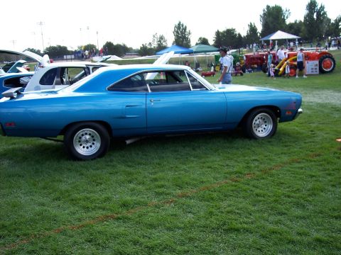 1972 Ford Ranchero - A blue 1970 Plymouth Road Runner is displayed at an outdoor event with other vehicles and people in the background.