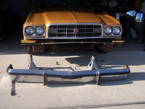 1973 Ford Ranchero - A gold 1973 Ford Ranchero is shown with its front bumper removed and resting on jack stands in front of the vehicle.