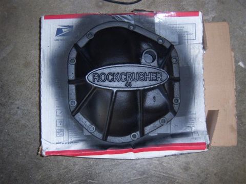 1995 Ford Bronco - A black differential cover with "ROCKCRUSHER 44" is shown on a cardboard box, with spray paint overspray.