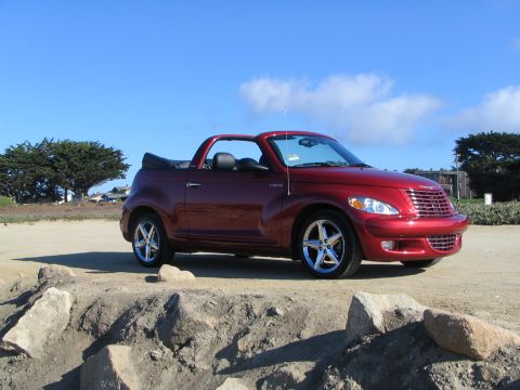 2005 Chrysler PT Cruiser - Red 2005 Chrysler PT Cruiser convertible parked on a dirt embankment with trees and sky in the background.
