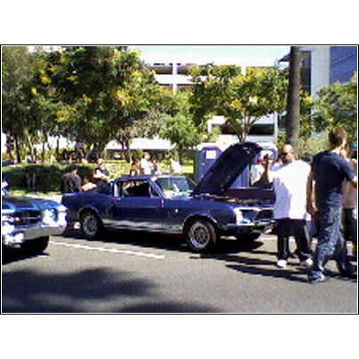 2007 Ford Ranchero - A blue coupe utility vehicle is displayed with its hood open, surrounded by onlookers.