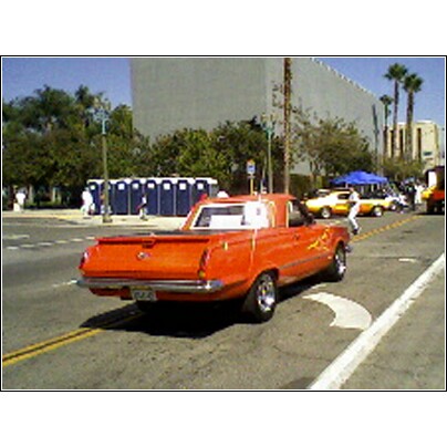 2007 Ford Ranchero - A bright orange coupe utility with flame decals is seen from the rear on a city street.