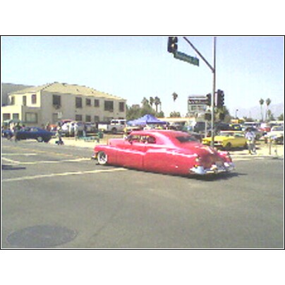 2007 Ford Ranchero - A pink custom coupe is seen from the rear at an intersection with other vehicles present.