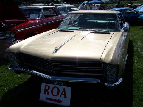 1972 Ford Ranchero - A gold sedan is displayed at an outdoor car show, with other vehicles and tents in the background.