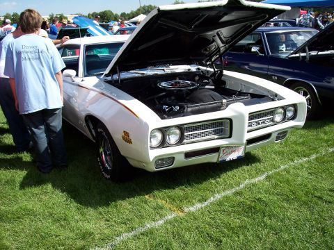 1972 Ford Ranchero - A white 1969 Pontiac GTO is displayed with its hood open at an outdoor car show.