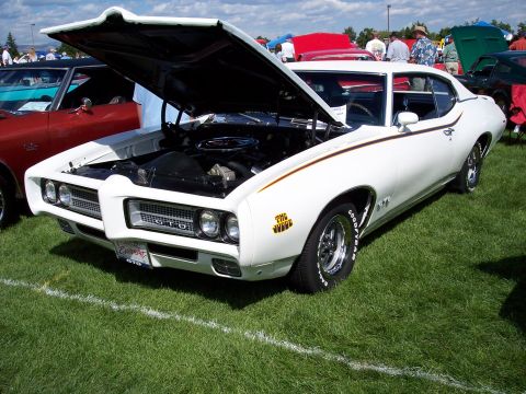 1972 Ford Ranchero - A white 1969 Pontiac GTO is displayed with its hood open on a grassy field.