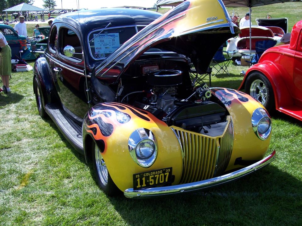 Hot rod with yellow fenders and flames, hood open showing engine. Colorado license plate 11-5707