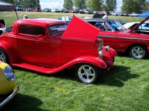 1972 Ford Ranchero - Two classic cars are parked on a grassy field at an outdoor event, with their hoods open.
