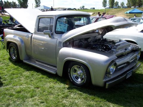 1972 Ford Ranchero - A silver 1956 Ford F-100 pickup truck is displayed with its hood and trunk open at an outdoor car show.