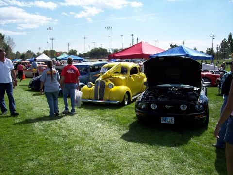 1972 Ford Ranchero - Two coupes are displayed on a grassy field under a partly cloudy sky at an outdoor car show.