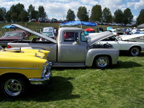 1972 Ford Ranchero - A silver 1956 Ford F-100 pickup truck is displayed with its hood open at an outdoor car show.