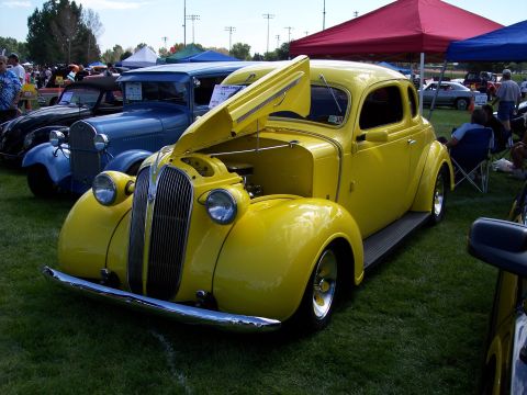 1972 Ford Ranchero - A bright yellow coupe with its hood open sits on display at an outdoor car show.