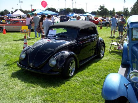 1972 Ford Ranchero - A black convertible Volkswagen Beetle is displayed on a grassy field at an outdoor car show.