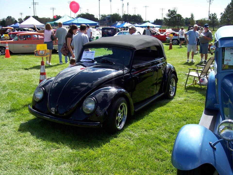 Black convertible Volkswagen Beetle with chrome wheels on grass