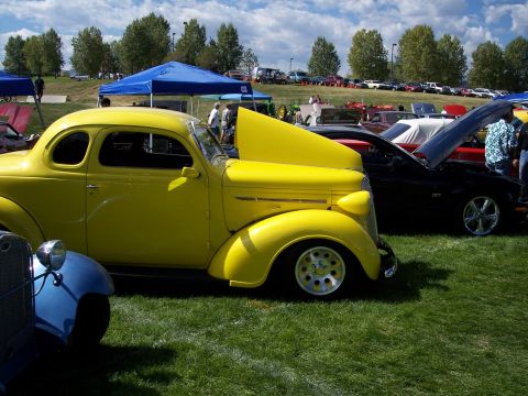 1972 Ford Ranchero - A bright yellow coupe is displayed with its hood open at a car show, alongside other vehicles.