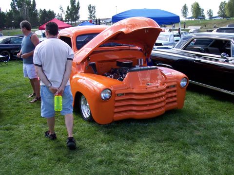 1972 Ford Ranchero - A vintage orange pickup truck is displayed with its hood open at an outdoor event.