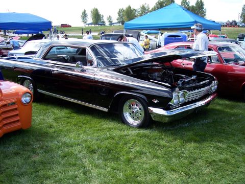 1972 Ford Ranchero - Black 1962 Chevrolet Impala coupe at an outdoor car show, hood open revealing the engine.