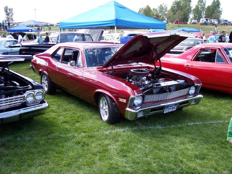 1972 Ford Ranchero - A red coupe is displayed with its hood open at an outdoor car show, with other vehicles and tents visible.