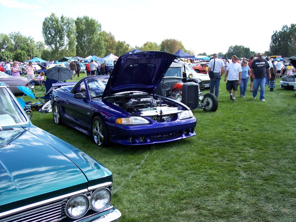 Purple convertible with hood open, showing engine. Chrome wheels. Parked on grass at car show