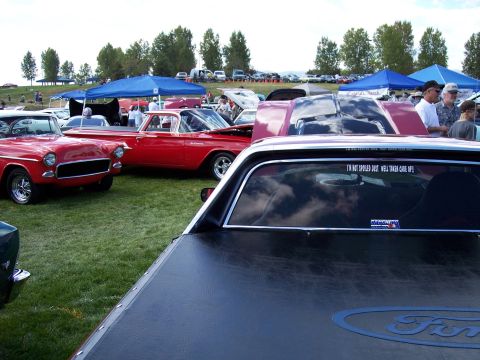 1972 Ford Ranchero - A red 1972 Ford Ranchero is parked at an outdoor car show, a black tonneau cover and a humorous sticker on the rear window.
