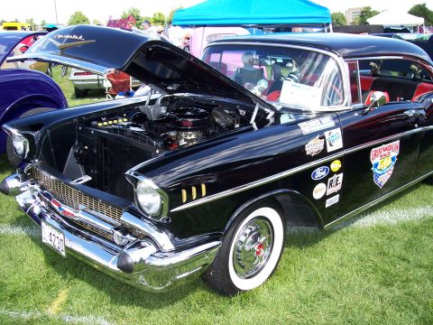 1972 Ford Ranchero - A black 1957 Chevrolet with its hood open, displaying the engine and adorned with various decals.