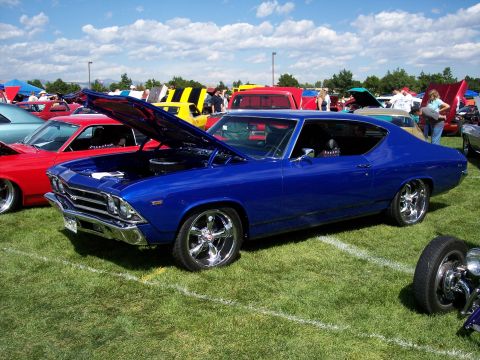 1972 Ford Ranchero - A bright blue 1969 muscle car is displayed with its hood open at an outdoor car show, surrounded by other vehicles.