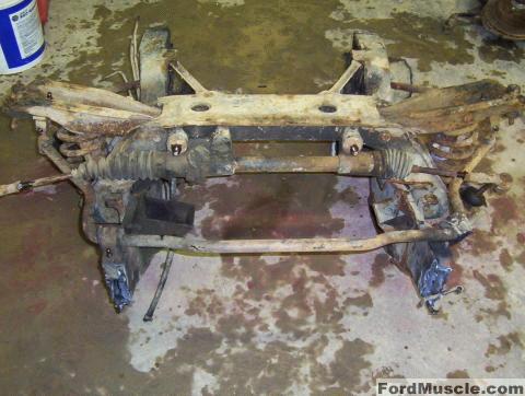 1964 Ford Fairlane - A disassembled front subframe assembly, likely for a Ford vehicle, showing the steering rack and suspension parts.