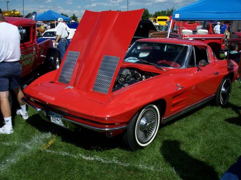 1972 Ford Ranchero - A red 1963 Chevrolet Corvette Stingray coupe is displayed with its hood open, revealing the engine, at an outdoor car show.