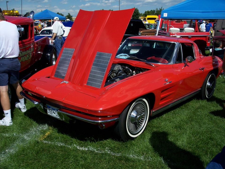 Red 1963 Corvette Stingray coupe, hood open, showing engine. Whitewall tires, wire wheels