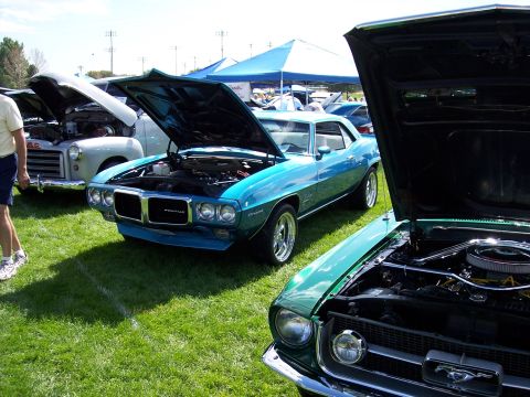 1972 Ford Ranchero - A blue 1969 Pontiac Firebird is displayed with its hood open at an outdoor car show.