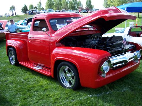 1972 Ford Ranchero - A bright red 1955 Ford F-100 pickup truck is displayed with its hood open, revealing the engine compartment.