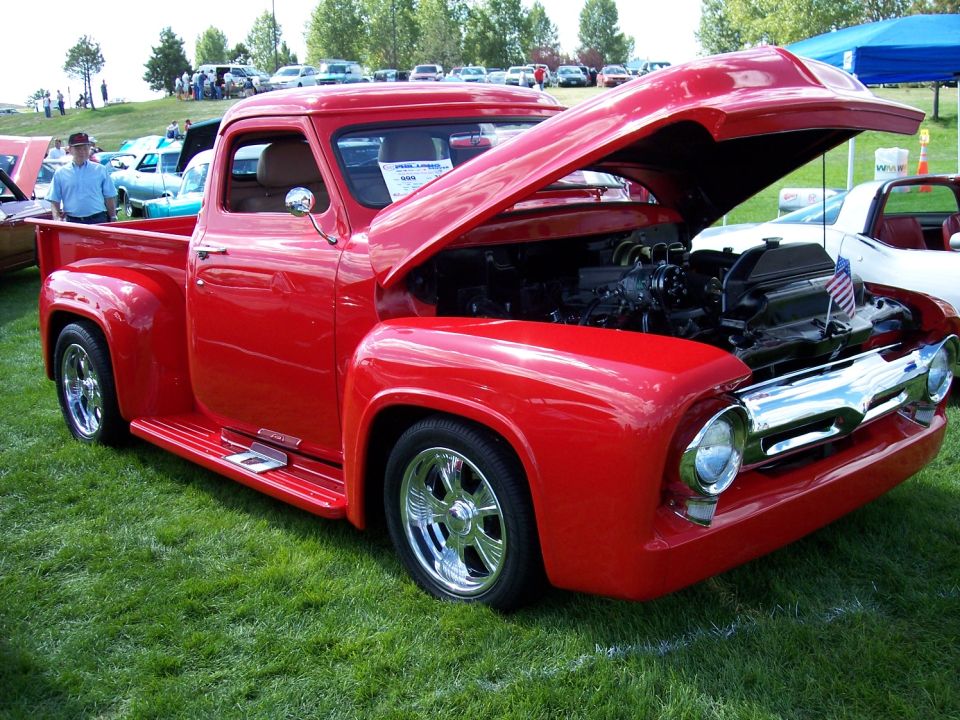 Red 1955 Ford F-100 pickup truck, hood open, showing engine