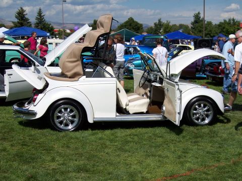 1972 Ford Ranchero - A white convertible Volkswagen Beetle with its doors and top open sits on display at an outdoor car show.