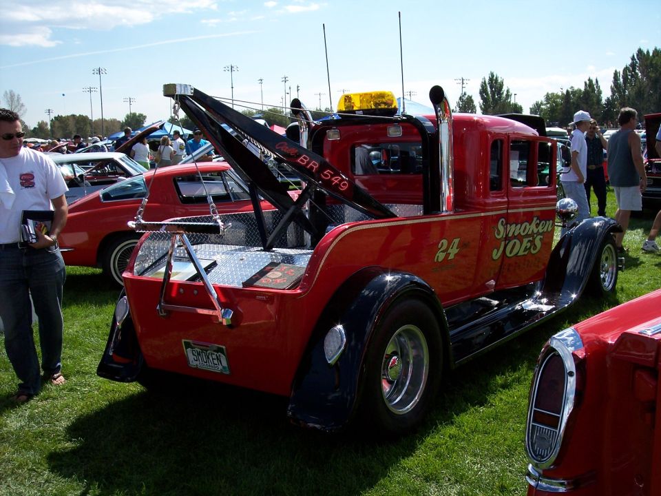 Red custom tow truck with 'Smoken JOE'S' painted on the side, parked on grass at an outdoor event