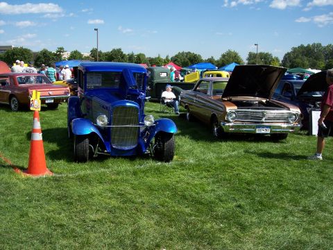 1972 Ford Ranchero - A blue hot rod truck is displayed at an outdoor car show with other vehicles.