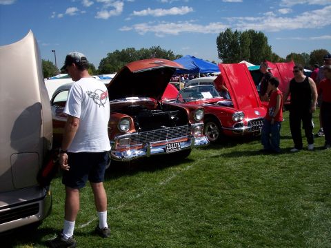 1972 Ford Ranchero - Several classic cars are on display at an outdoor event, with one orange vehicle prominently featured.