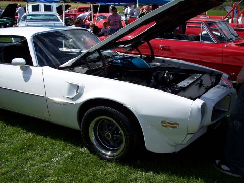 1972 Ford Ranchero - White 1970-1973 Pontiac Firebird Trans Am at an outdoor car show, hood raised to reveal the engine.