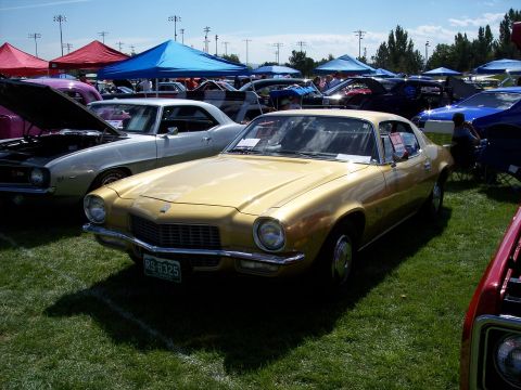 1972 Ford Ranchero - A gold 1970 Chevrolet Camaro is parked on grass at an outdoor car show.