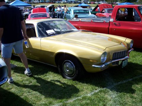 1972 Ford Ranchero - A gold coupe with a distinctive grille and bumper is displayed at an outdoor car show.