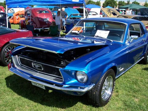1972 Ford Ranchero - A blue 1967 Ford Mustang is displayed with its hood open at an outdoor car show.