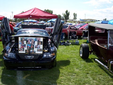 1972 Ford Ranchero - A black car with its doors open displays a collage of photos at an outdoor car show.