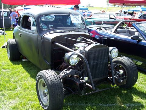 1972 Ford Ranchero - A matte black hot rod coupe sits on display at an outdoor car show.