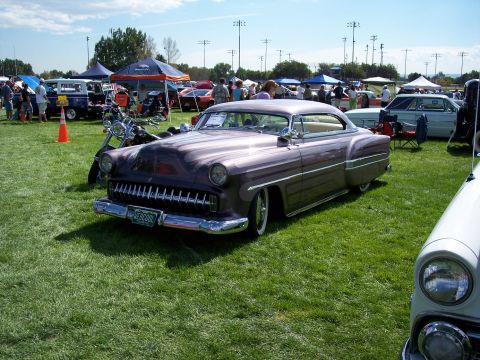 1972 Ford Ranchero - A customized 1950s coupe, painted purple with flame graphics, is displayed at an outdoor car show.