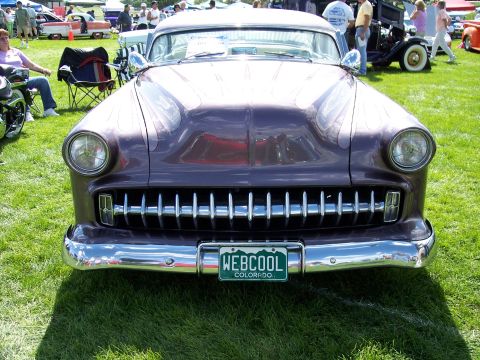 1972 Ford Ranchero - A purple 1954 Chevrolet Bel Air with flame decals is parked on grass at an outdoor car show.