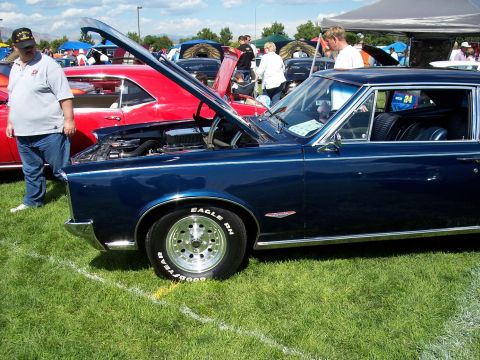 1972 Ford Ranchero - A dark blue coupe, possibly a 1965 model, is displayed with its hood open at an outdoor car show.