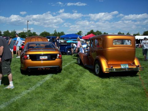 1972 Ford Ranchero - Two vintage cars, a GTO and a sedan, are displayed on a grassy field under a partly cloudy sky.