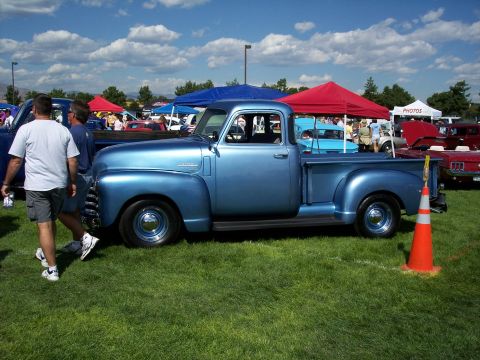1972 Ford Ranchero - A classic blue pickup truck is displayed at an outdoor event with other vehicles and tents.