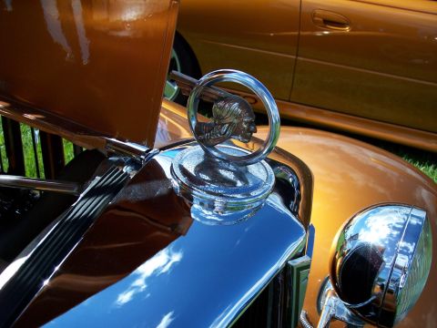 1972 Ford Ranchero - Close-up of a vintage car's hood ornament, with another vehicle in the background.